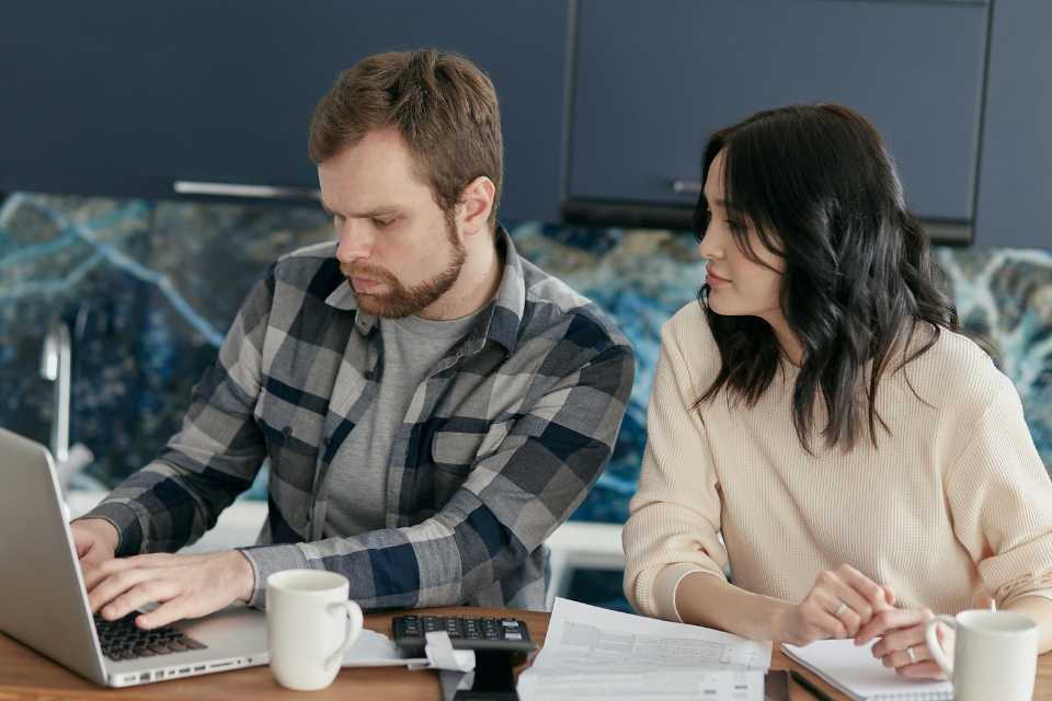 young couple budgeting for flooring renovation at modern blue kitchen island